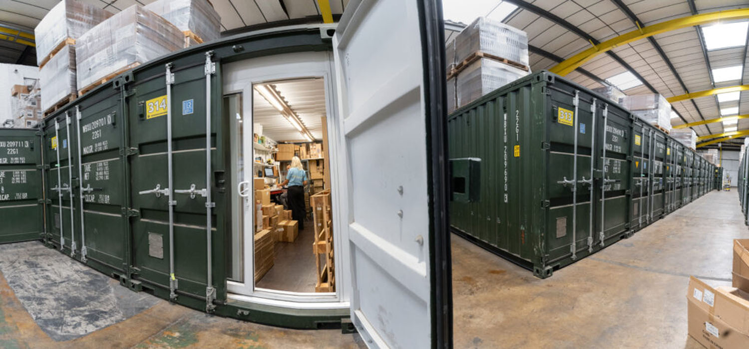 Rows of green storage containers inside the warehouse with one open to show shelving