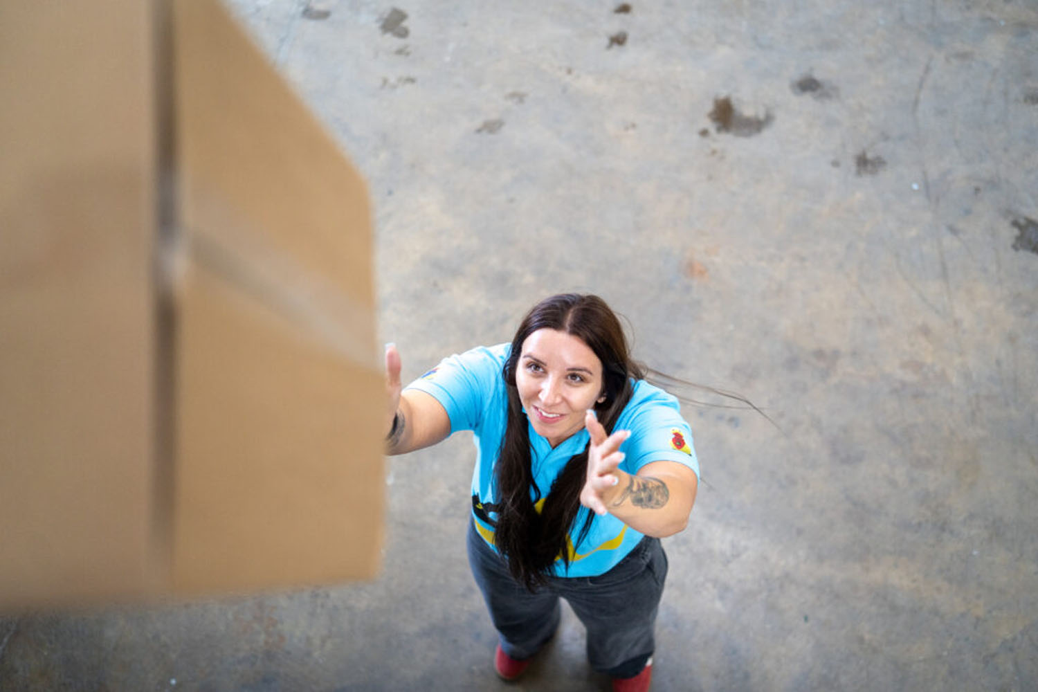 Team member reaching up to take a cardboard box
