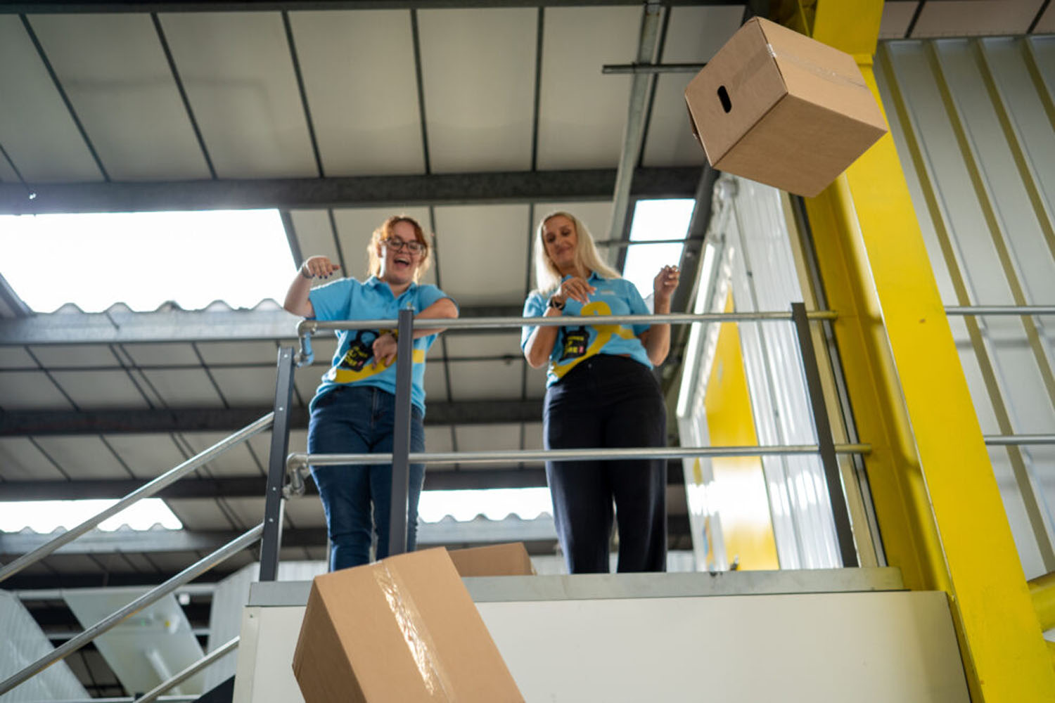 Team members passing cardboard boxes down from the mezzanine walkway