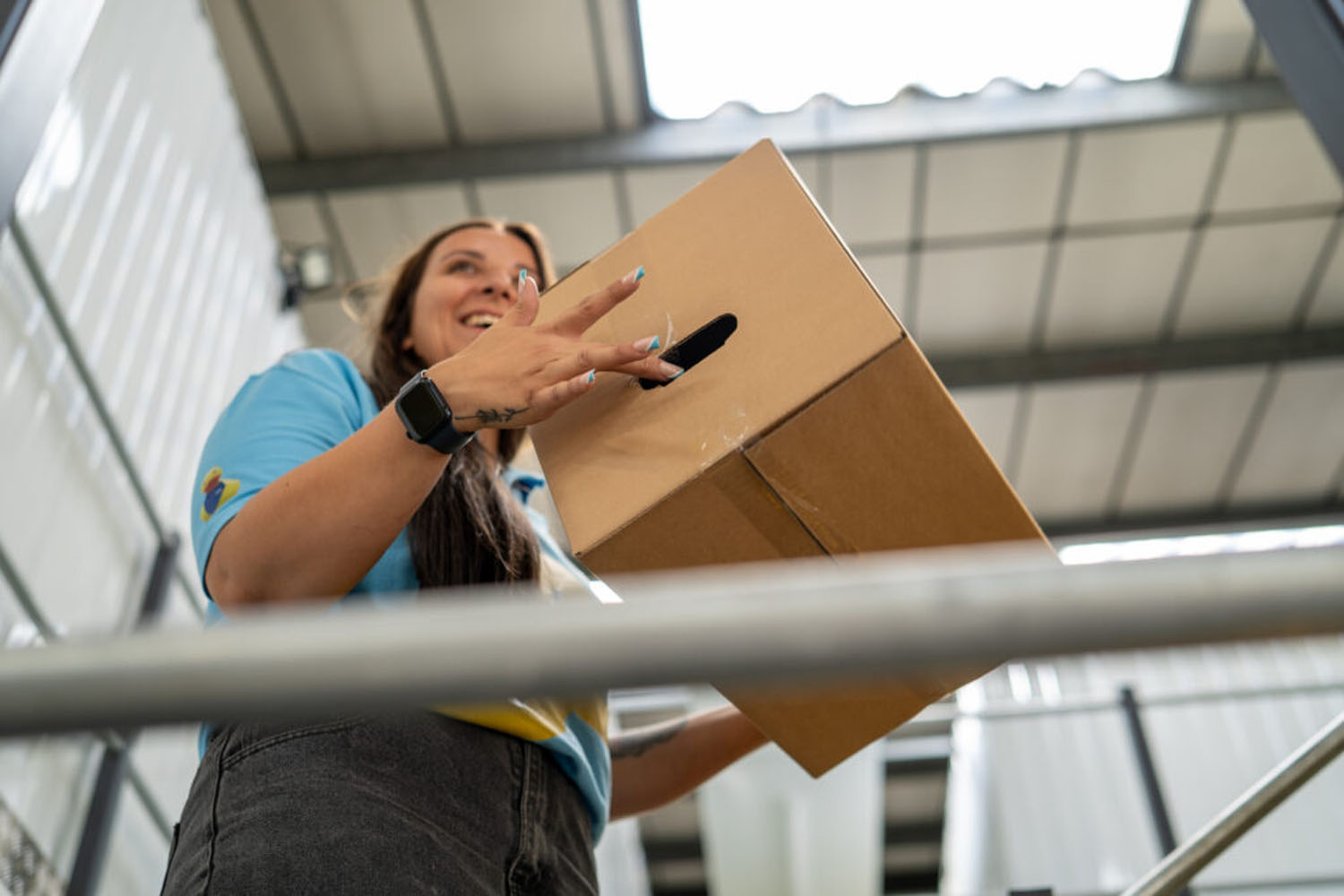 Team member passing a cardboard box down from the mezzanine