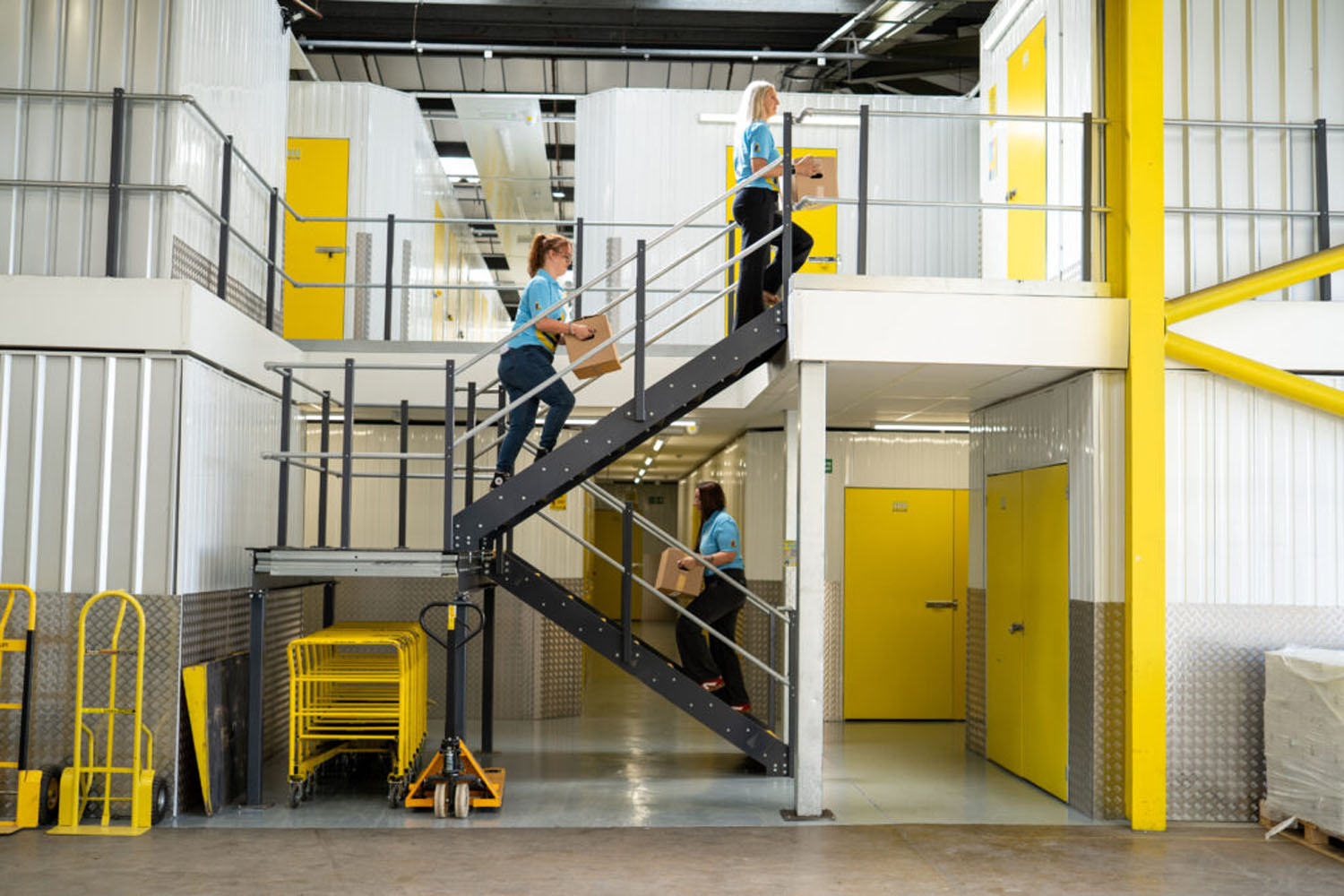 Staff carrying boxes up the stairs inside the indoor storage facility