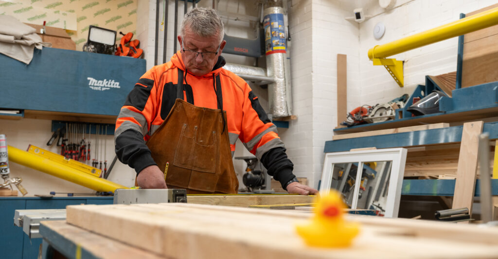 Joiner working at a bench saw inside a trade pod